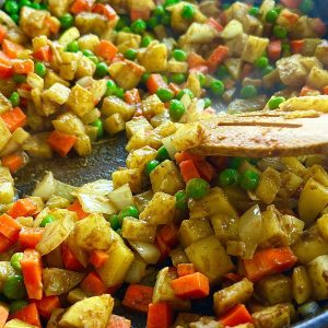 adding carrot and peas to curry puff