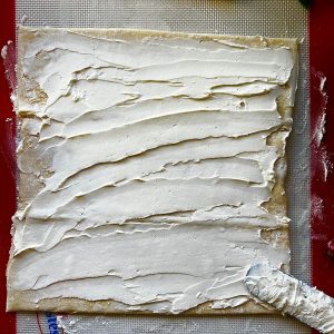 spreading cream cheese on pastry dough